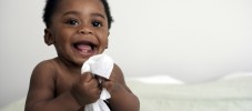 baby holding wipe smiling