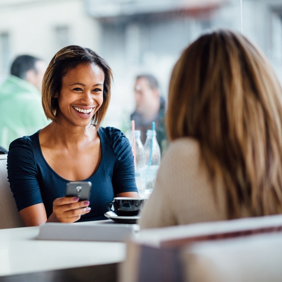 Multi ethnic Friends talking and laughing in coffee shop