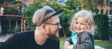 Happy father looking at daughter while holding son in park