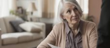 Senior Caucasian woman holding papers at desk