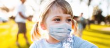 little girl playing at the park with the protective mask