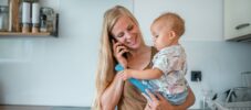Mature Caucasian woman holding her baby in her hands and making a phone call