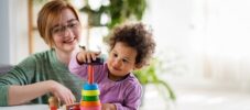 Mother looking at a child playing with an educational didactic toy