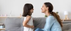 Mother spend time with little daughter talking sitting on couch