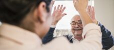 Happy senior man with raised hands looking at young woman