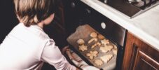 Girl takes Christmas cookies out of the oven.